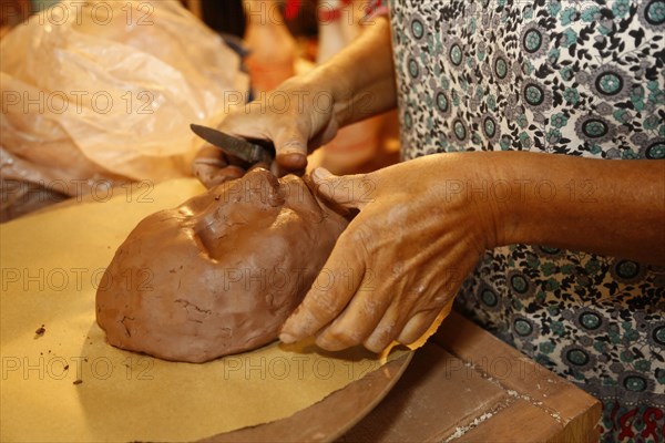 Mixed race woman shaping clay mask in art studio