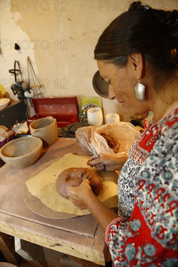 Mixed race woman shaping clay mask in art studio