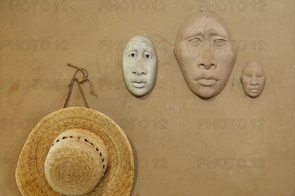 Clay masks and hat hanging on wall