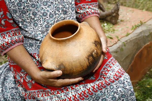 Woman sitting and holding clay pot