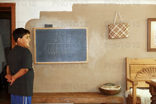Proud Native American boy standing near equation on blackboard