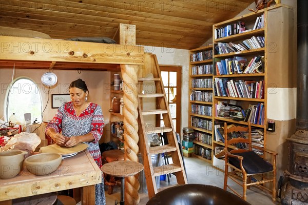 Mixed race woman shaping clay in art studio