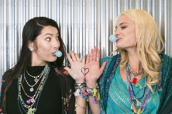 Women chewing gum and showing heart on hands