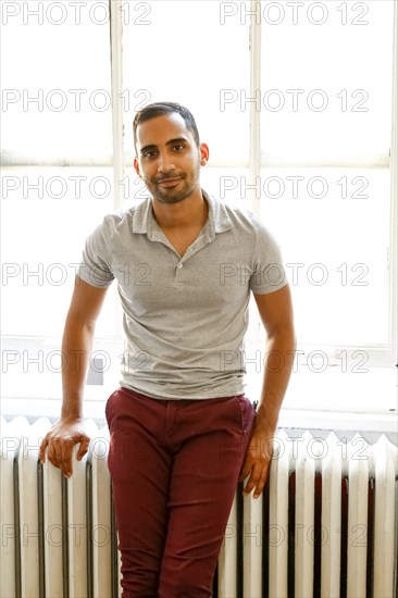 Mixed race man leaning on radiator