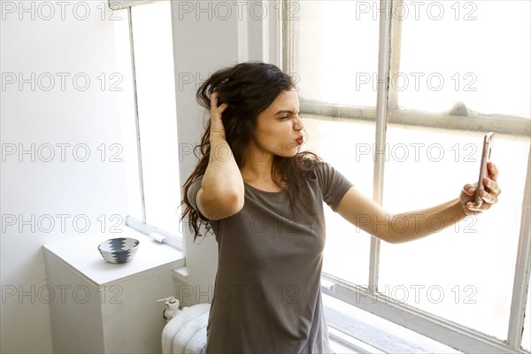 Mixed race woman posing for cell phone selfie