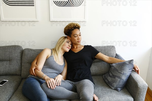 Women cuddling on sofa