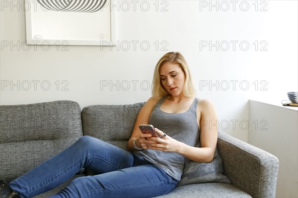 Caucasian woman sitting on sofa texting on cell phone