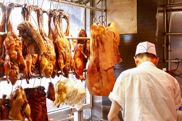 Butcher standing near hanging meat