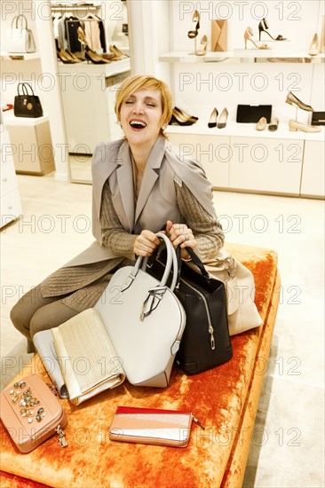 Laughing Caucasian woman holding purses in store