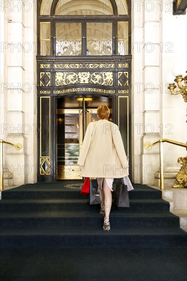 Glamorous Caucasian woman carrying shopping bags to luxury building