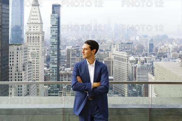 Caucasian businessman leaning on urban rooftop