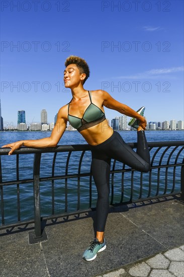 Mixed race woman stretching legs at waterfront