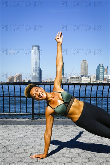 Mixed race woman balancing on arm at waterfront