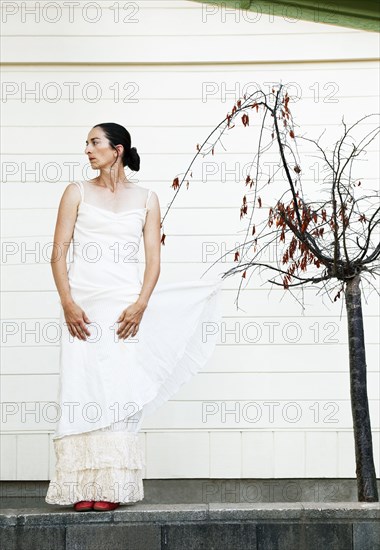 Caucasian woman with wedding dress caught on tree