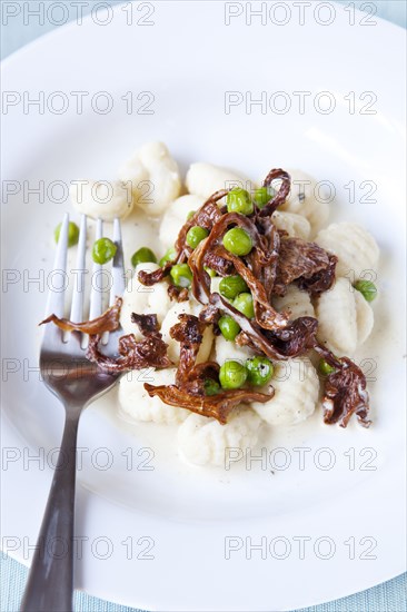 Gnocchi and peas in bowl with fork