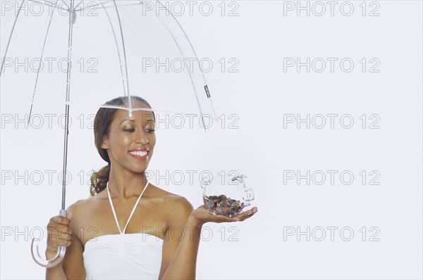 Young woman holding a piggy bank and an umbrella