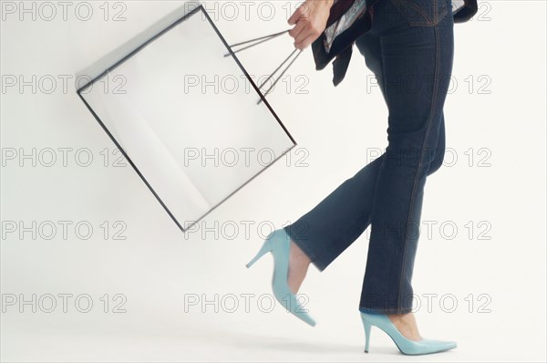 Studio shot of woman walking with shopping bag