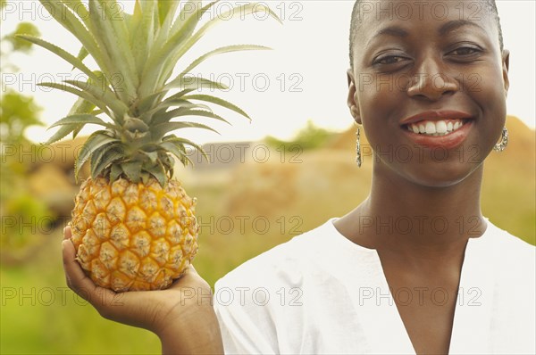 African American woman holding pineapple outdoors