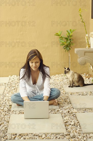 Woman with laptop and cat outdoors