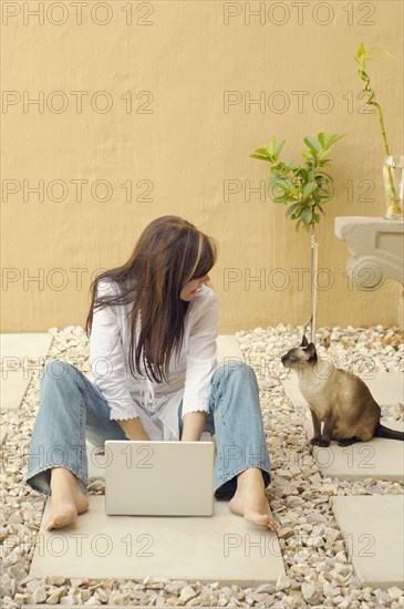 Woman with laptop and cat outdoors