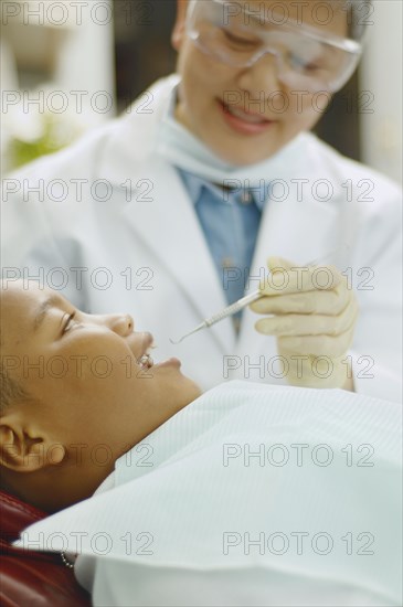 Senior Asian female dentist working on African boy