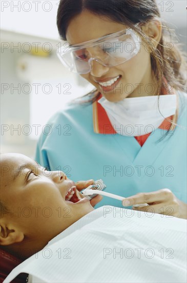 Indian female dental assistant working on African boy