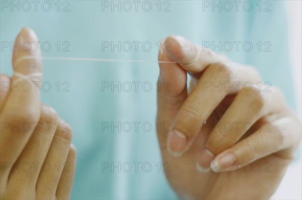 Close up of woman's hands with dental floss
