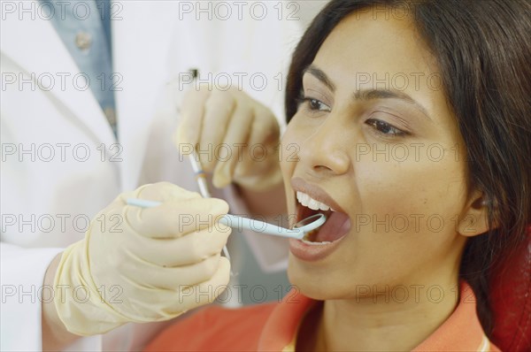 Dentist holding dental mirror in female patient's mouth