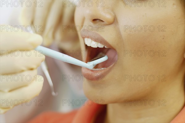 Dentist holding dental mirror in female patient's mouth