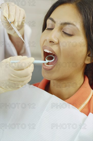 Dentist holding dental mirror in female patient's mouth