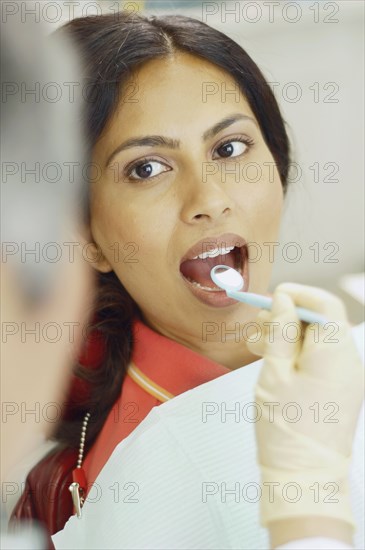 Dentist holding dental mirror in female patient's mouth
