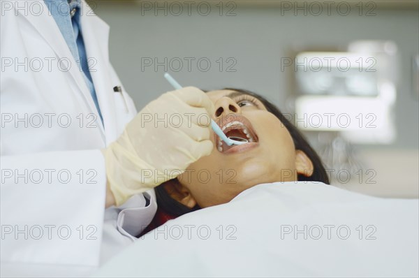 Dentist holding dental mirror in female patient's mouth