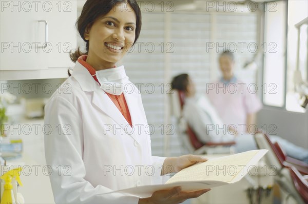 Indian female dentist holding chart and smiling