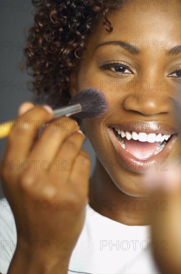 Close up of African woman applying make up