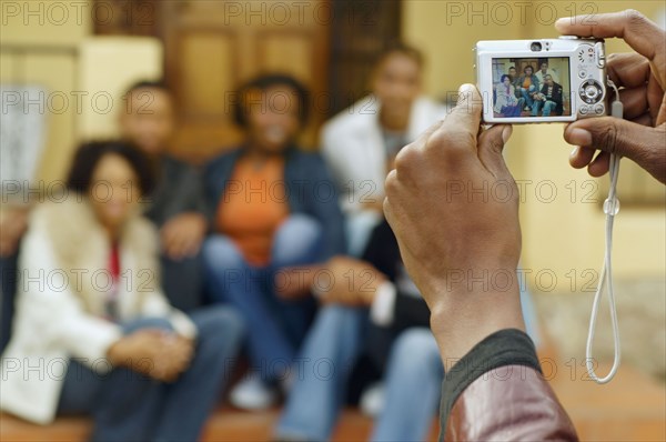 African man taking photograph of friends