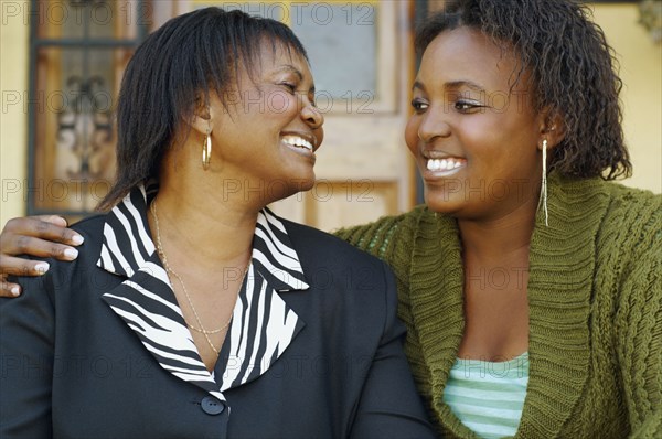 African mother and adult daughter smiling at each other