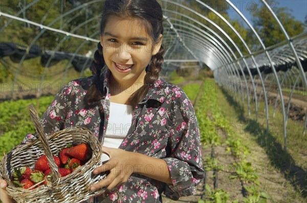 Hispanic girl holding basket of organic strawberries