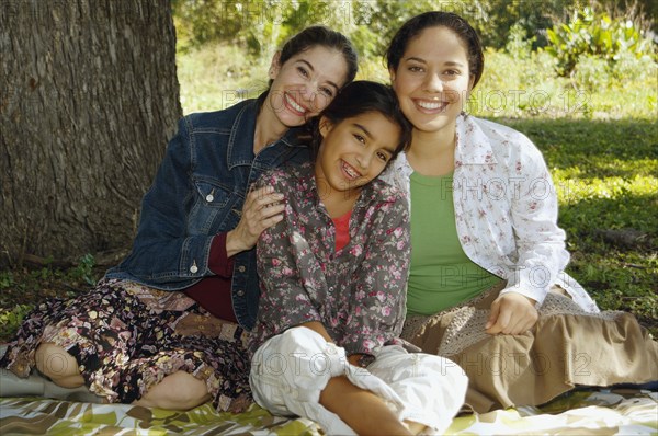 Multi-ethnic family sitting under tree