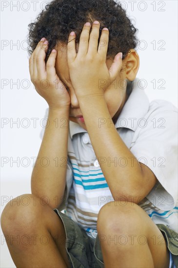 Mixed race boy with head in hands