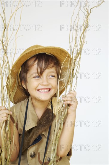 Mixed race boy in safari outfit holding branches