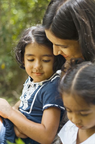 Indian mother sitting with daughters outdoors