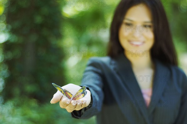 Hispanic businesswoman holding butterfly