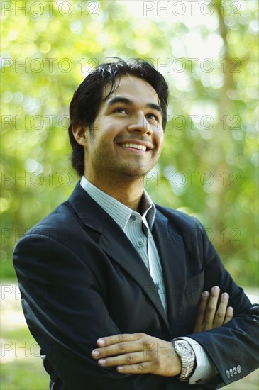 Hispanic businessman looking up with arms crossed