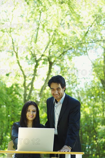 Hispanic business people using laptop outdoors