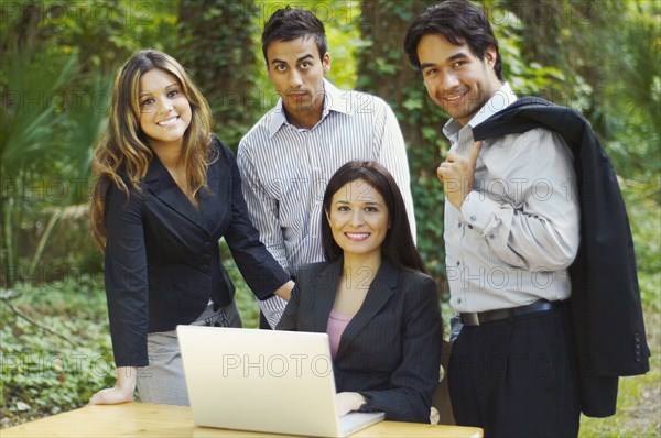 Hispanic business people using laptop in woods