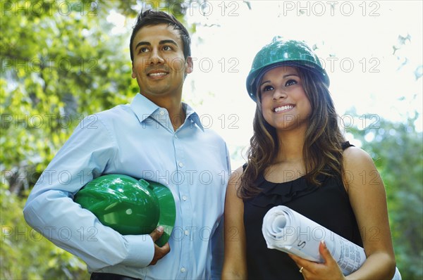 Hispanic business people with green hard hats