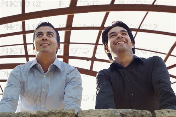 Hispanic businessmen leaning on wall