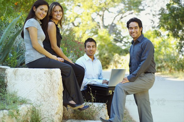 Hispanic business people using laptop outdoors
