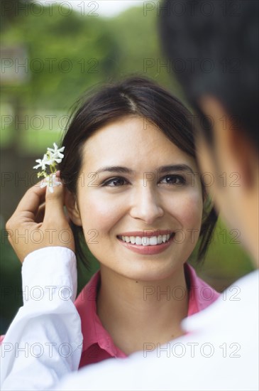 Hispanic husband putting flower behind wife's ear