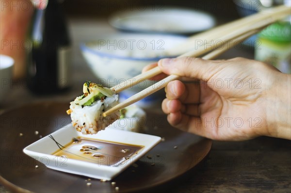 Person eating sushi with chopsticks